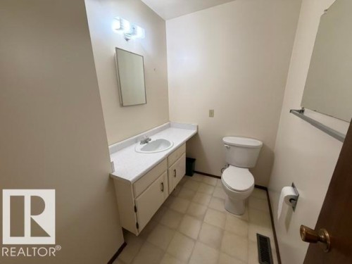 Bathroom featuring a vanity with an integrated sink, built-in cabinetry, wall-mounted mirror, and tile flooring - 3 Morgan Crescent, St. Albert, AB 