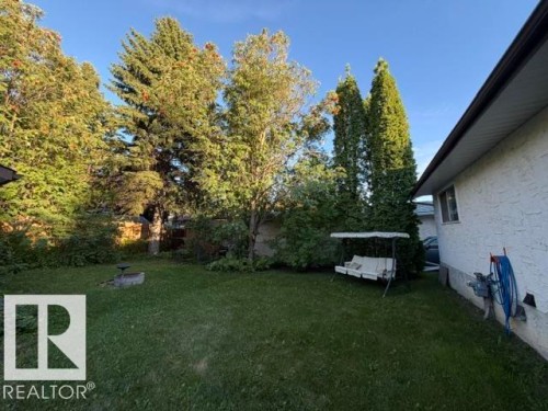 Expansive backyard featuring a manicured lawn, established trees, and a built-in fire pit - 3 Morgan Crescent, St. Albert, AB 