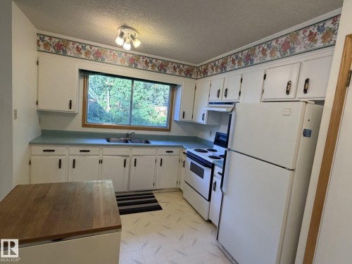 Kitchen featuring white cabinetry, light blue countertops, a double basin sink, and a window above the sink - 3 Morgan Crescent, St. Albert, AB 