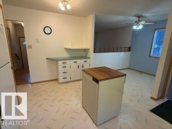 Kitchen with light-toned flooring, white cabinetry, and a butcher block top island - 