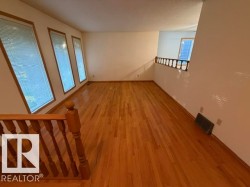 Hardwood flooring throughout, multiple windows with blinds, wood railing, and a neutral color palette - 
