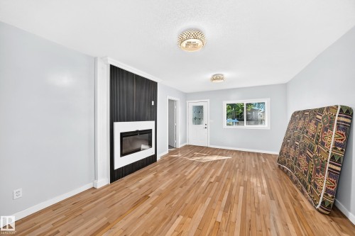 Hardwood flooring throughout, featuring a modern fireplace with a white and black surround - Edmonton, AB 