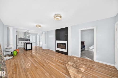 Hardwood flooring throughout, a built-in electric fireplace with a black accent wall, and recessed lighting - Edmonton, AB 