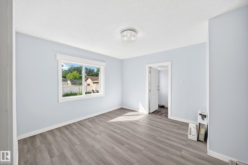Light blue walls with white trim, wood-finish flooring, and a crystal flush mount ceiling light fixture - Edmonton, AB 