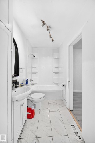 Bathroom featuring a white vanity with an integrated sink, track lighting, and a bathtub with a shower - Edmonton, AB 
