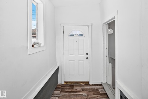 Wood-finish flooring, white paneled entry door, transom window, and white trim accents - Edmonton, AB 