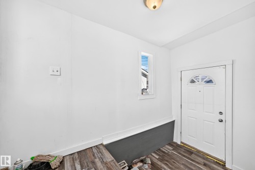 Entry area with wood-finish flooring, white paneled door, and a transom window - Edmonton, AB 