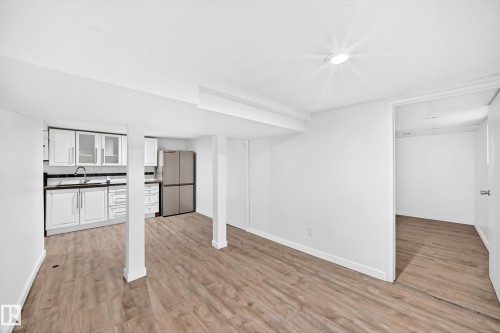 Kitchenette with white cabinetry, stainless steel sink, dark countertops, and tile backsplash - Edmonton, AB 