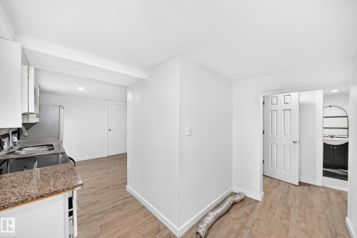White cabinetry, speckled countertop, stainless steel sink, and wood-finish flooring - Edmonton, AB 