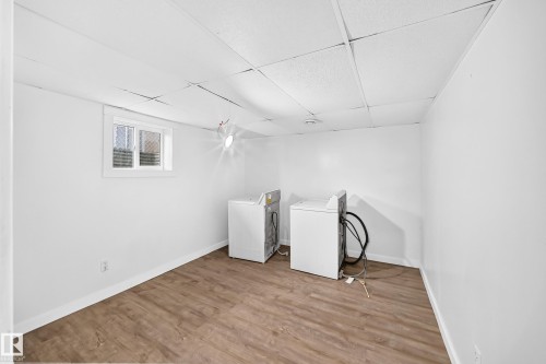 Laundry area featuring wood-finish flooring, white walls, and a drop ceiling - Edmonton, AB 