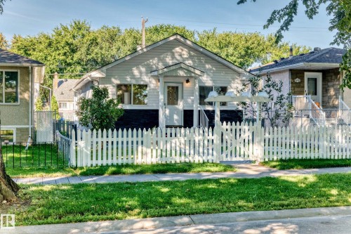 White picket fence enclosing a front yard with mature trees and a manicured lawn - Edmonton, AB 