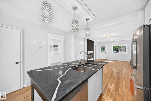 Kitchen island with a double basin sink, stainless steel faucet, and dark counters - Edmonton, AB 