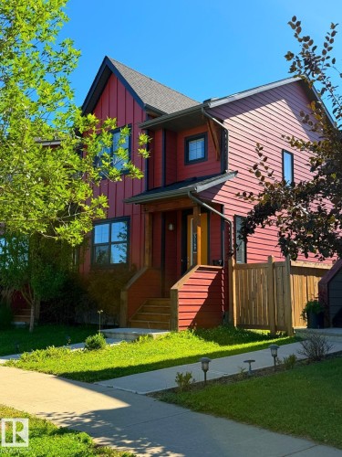 Two-story residence featuring red vertical and horizontal siding, a covered porch entrance, and a dark shingle roof - 5169 Chappelle Rd Southwest, Edmonton, AB 