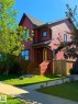 Two-story residence featuring red vertical and horizontal siding, a covered porch entrance, and a dark shingle roof - 5169 Chappelle Rd Southwest, Edmonton, AB 