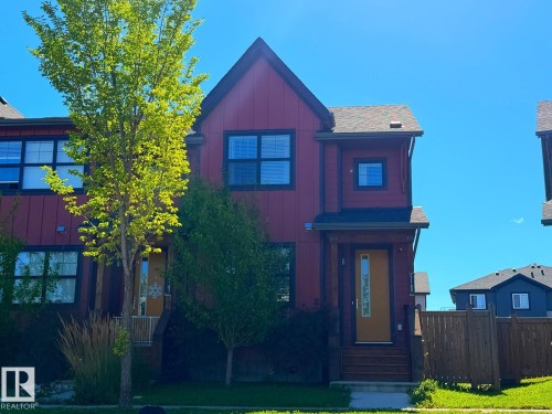 Red siding exterior with dark trim windows, front entry with covered porch, and brown wood fencing - 5169 Chappelle Rd Southwest, Edmonton, AB 