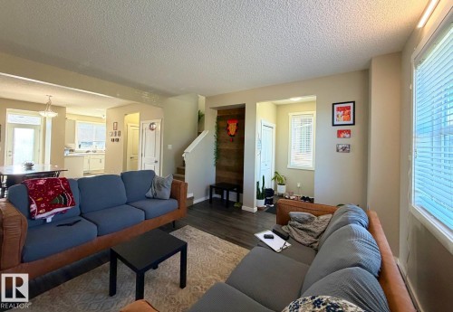 Open-concept living area featuring wood-finish flooring and multiple windows - 5169 Chappelle Rd Southwest, Edmonton, AB 