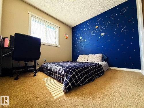 Carpeted room featuring a window with blinds, a built-in wall mural, and neutral wall paint - 5169 Chappelle Rd Southwest, Edmonton, AB 