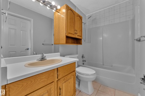 Wood-finish vanity with integrated sink, chrome faucet, and overhead wood-finish cabinetry - 3227 145 Avenue Nw, Edmonton, AB 