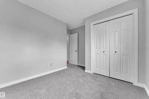 Light gray wall paint with white trim, gray carpet, and white bi-fold closet doors - 3227 145 Avenue Nw, Edmonton, AB 