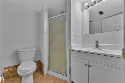 White vanity with integrated sink, white tiled backsplash, chrome faucet, and mirrored medicine cabinet - 3227 145 Avenue Nw, Edmonton, AB 