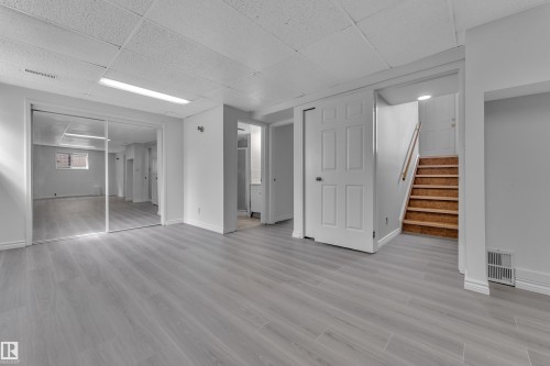 Spacious interior featuring light wood-finish flooring, white walls, and a drop ceiling with recessed lighting - 3227 145 Avenue Nw, Edmonton, AB 
