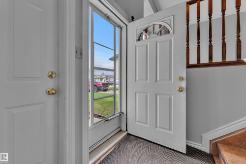 Entryway featuring a paneled door with an arched transom window, a storm door, and a wood-finish staircase - 3227 145 Avenue Nw, Edmonton, AB 