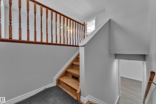 Staircase with wood-finish treads and risers, complemented by a wood-finish railing and balusters - 3227 145 Avenue Nw, Edmonton, AB 