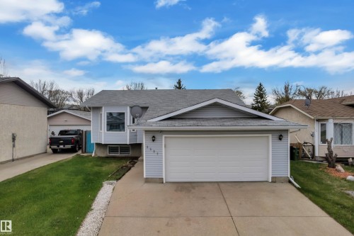 Light blue siding exterior with a pitched roof, attached garage, concrete driveway, and front lawn - 3227 145 Avenue Nw, Edmonton, AB 