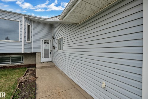 Light gray siding exterior with multiple windows, a concrete walkway, and an entry door - 3227 145 Avenue Nw, Edmonton, AB 