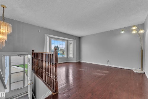 Hardwood flooring, bay window, wood staircase with balusters, and a tiered chandelier - 3227 145 Avenue Nw, Edmonton, AB 