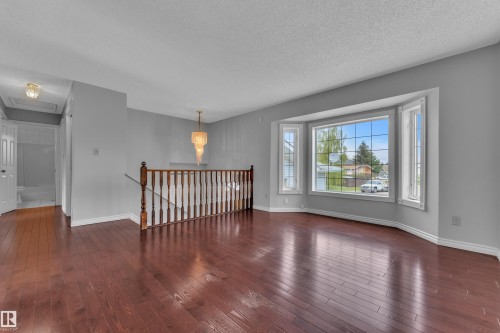 Rich wood-finish flooring throughout, bay window, chandelier, and a wood banister - 3227 145 Avenue Nw, Edmonton, AB 
