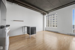 Hardwood-style flooring, high ceilings, exposed ductwork, large windows, and a built-in oven - 