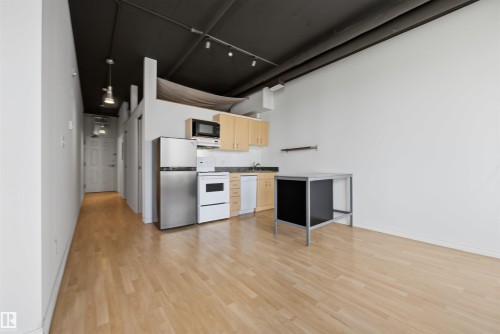 Wood-finish flooring, high ceilings with exposed ductwork, and track lighting - #1313 10024 Jasper Av Nw, Edmonton, AB 