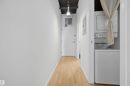 Wood-finish flooring with a white paneled door, black ceiling, and exposed ductwork - #1313 10024 Jasper Av Nw, Edmonton, AB 