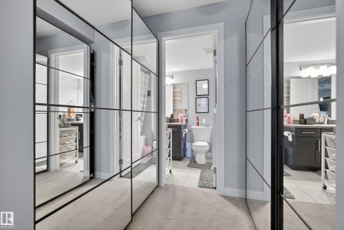 Mirrored closet doors with black framing, light gray wall paint, and carpeted flooring - #107 1031 173 St Sw, Edmonton, AB 