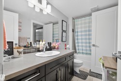 Contemporary vanity with dark wood-finish cabinetry, integrated rectangular sink, and a large wall-mounted mirror - 