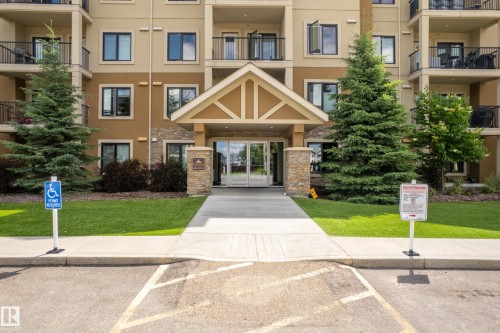 Multi-story building with a stone-accented entrance, covered entryway, and glass double doors - #107 1031 173 St Sw, Edmonton, AB 