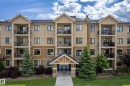 Modern multi-unit residential building featuring a symmetrical façade with peaked gable rooflines, tan exterior cladding, and black-trimmed windows across four stories - #107 1031 173 St Sw, Edmonton, AB 