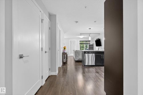 Hardwood-finish flooring throughout, white interior doors with contemporary hardware, recessed lighting, stainless steel dishwasher, and dark cabinetry - #107 1031 173 St Sw, Edmonton, AB 