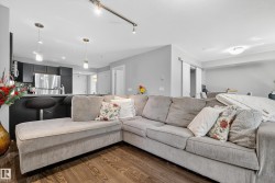 Open-concept living area with wood-finish flooring, track lighting, and a breakfast bar with pendant lights - 