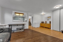 Mixed-tone wood-finish flooring, white walls, built-in cabinetry, and a large pass-through window - 