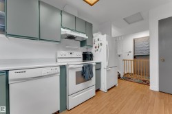Kitchen featuring wood-finish flooring, white appliances, light gray cabinetry, and a skylight - 