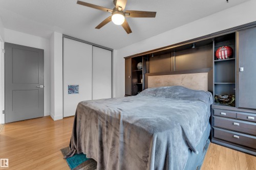 Built-in cabinetry with integrated lighting, wood-finish flooring, ceiling fan with light fixture, sliding closet doors, and a two-panel interior door - 442 Kirkpatrick Crescent Nw, Edmonton, AB 