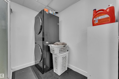 Stackable washer and dryer unit, white walls, and dark flooring - 442 Kirkpatrick Crescent Nw, Edmonton, AB 