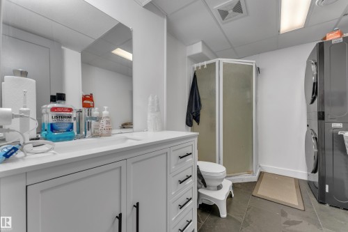 White vanity with matte black hardware, integrated sink, and large wall-mounted mirror - 442 Kirkpatrick Crescent Nw, Edmonton, AB 