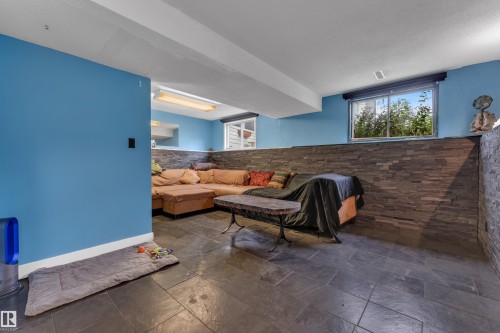 Slate tile flooring, accent wall with stacked stone finish, exposed ceiling beams, horizontal sliding window, and a built-in shelf - 442 Kirkpatrick Crescent Nw, Edmonton, AB 