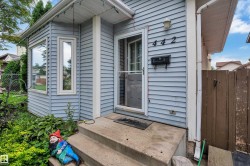 Light blue siding exterior with multiple windows, concrete front steps, and a side wooden fence - 