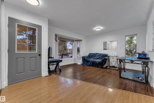 Entryway with light wood-finish flooring, leading into a living area with dark wood-finish flooring - 442 Kirkpatrick Crescent Nw, Edmonton, AB 