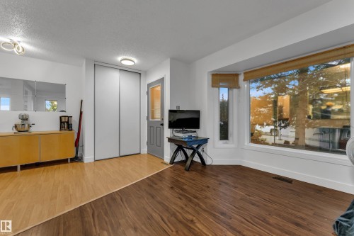 Bay window with natural light, wood-finish flooring, built-in mirrored wall accent, and a built-in storage unit - 442 Kirkpatrick Crescent Nw, Edmonton, AB 
