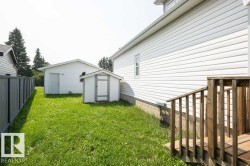Spacious backyard featuring a detached garage, a white storage shed, and a privacy fence - 